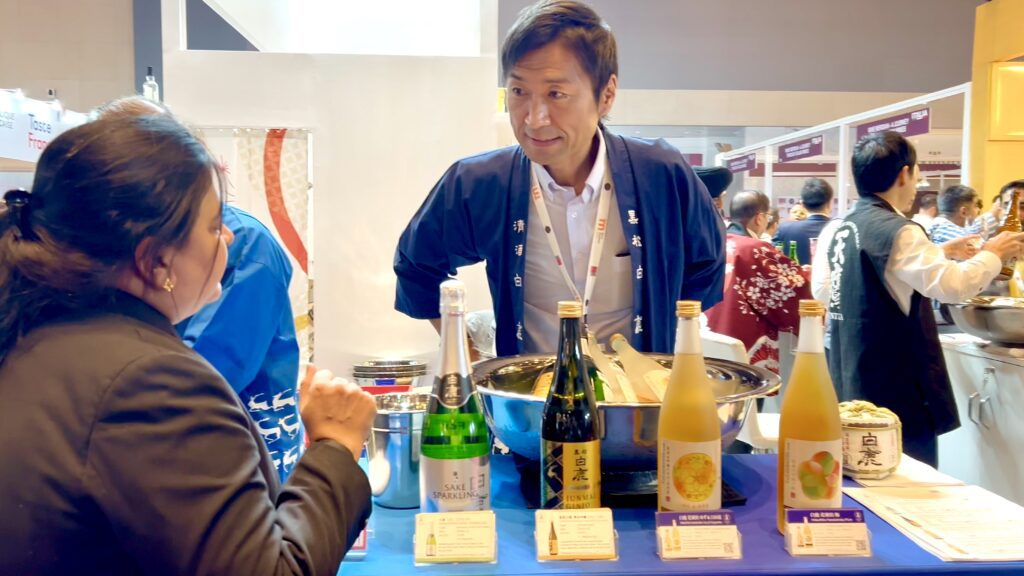 Hideki Matsuki, from Hakushika Sake interacting with a visitor at the Japanese Pavilion at Prowine Mumbai 2024