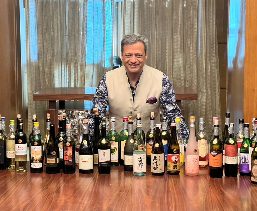 Ravi Joshi with a collection of wine and sake bottles at a blind tasting